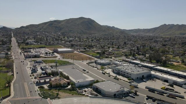 Compelling drone footage steadily pushes into the heart of Riverside, California, showcasing a blend of commercial and residential structures, all set against the serene backdrop of the Blue Mountain.