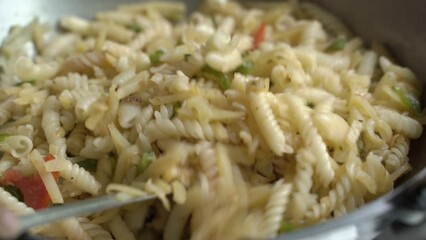 A woman prepares pasta at home with silverware.