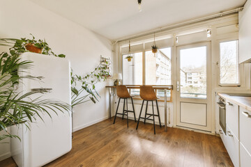 a kitchen and dining area in a small apartment with wood floors, white walls, and an open door leading to the patio
