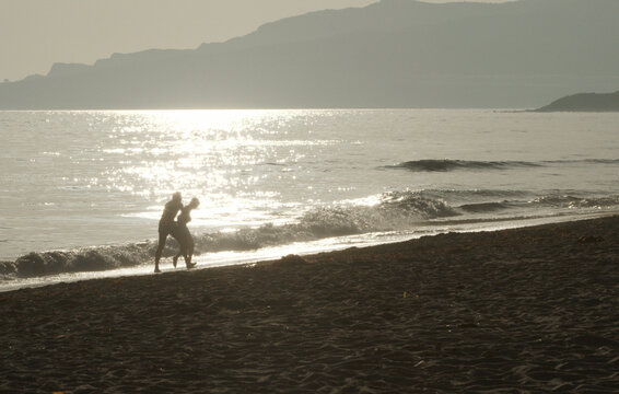 Silhouette of a happy couple playing at the glitterin beach