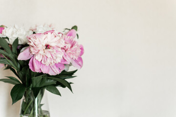 a bouquet of peonies in a glass vase on a light background. summer postcard. floral background