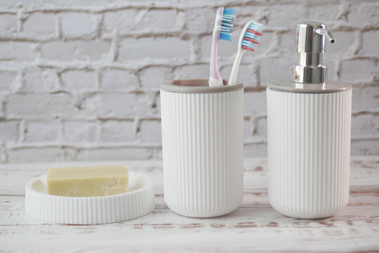 tooth brush in a white mug and soap on a case on table