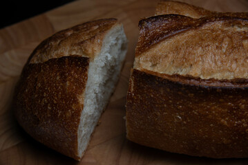 Homemade sourdough crusty loave of bread on wooden background.  Still life concept. Dark moody.
