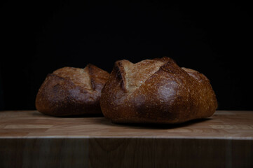Homemade sourdough crusty loave of bread on wooden background.  Still life concept. Dark moody.
