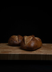 Homemade sourdough crusty loave of bread on wooden background.  Still life concept. Dark moody.

