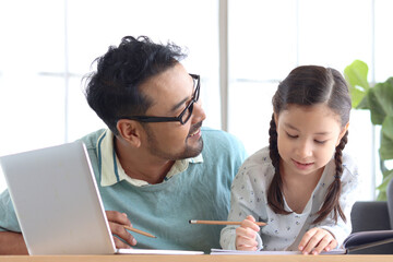 Father teaches cute girl daughter to do school homework, using laptop computer for e-learning study at home, happy family dad and kid spending time together for education and searching Internet.