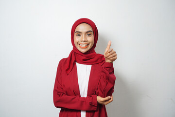 Asian business Muslim woman in red casual clothes smiling happily giving thumbs up