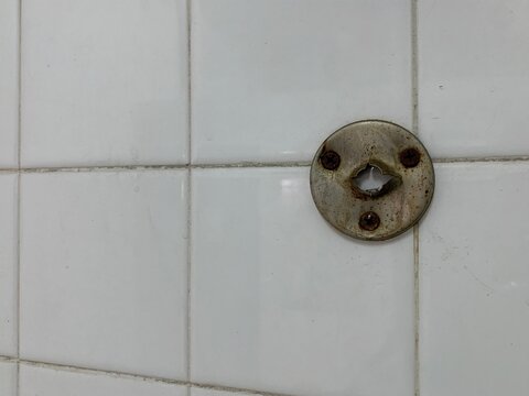 An old stainless steel hook with a hole resembling a face.