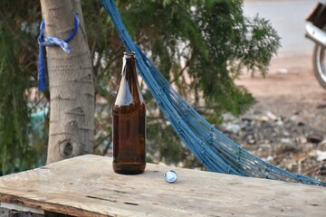 Liquor bottles lay on a wooden table, behind which a blue hammock hung from a tree.