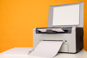 Front view of a multifunction device - printer, copier, scanner and a blank sheet of A4 paper on a white table  - obrazy, fototapety, plakaty