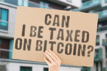 Man hand holding a banner with the text 'Can I be taxed on bitcoin' . fair taxation on cryptocurrency. tax return, economic, efficiency, saving, system, control