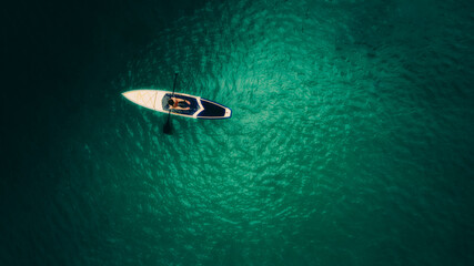 Aerial shot of beautiful green lagoon at hot summer day with small boat. Top view of girl in the boat.