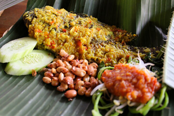 Traditional balinese food, Mujair Nyat-nyat, served on fresh banana leaf plating with various side...