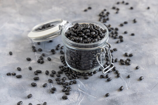 Glass jar full of dry black beans on grey table