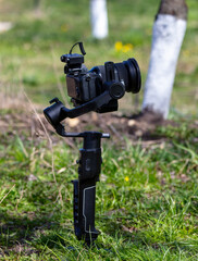 Professional video camera on tripod in green grass. Shallow depth of field