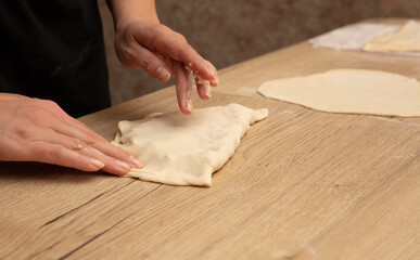 Fototapeta na wymiar Female hands kneading dough on a wooden table. Close-up