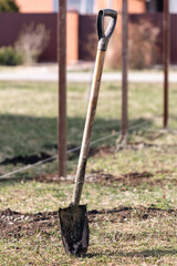 A worker digs the ground with a shovel to install a fence