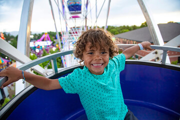 A cute African American little boy enjoying a Ferris Wheel ride at a local carnival during a summer vacation