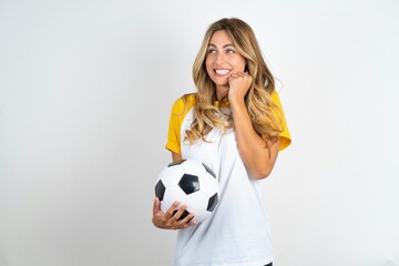 Young beautiful woman wearing football T-shirt over white background clenches fists and awaits for...