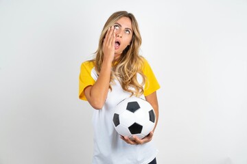 Young beautiful woman wearing football T-shirt over white background keeps hands on cheeks has bored displeased expression. Stressed hopeless model