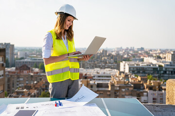 Young female construction specialist engineer reviewing blueprints at construction site