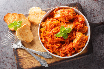 Homemade fish stew with vegetables in spicy tomato sauce served with toast close-up on a wooden board on the table. horizontal top view from above