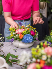 Florist arrangiert bunte Blumen in einem Gefäß aus Keramik, Blumengesteck mit frischen Blumen, 