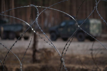 Razor wire with Ukrainian armed vehicles on background, ready for Ukrainian counteroffensive operation. Ukraine armed forces defending and regaining occupied territory - 614355843