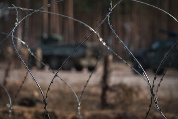Razor wire with Ukrainian armed vehicles on background, ready for Ukrainian counteroffensive operation. Ukraine armed forces defending and regaining occupied territory - 614355860