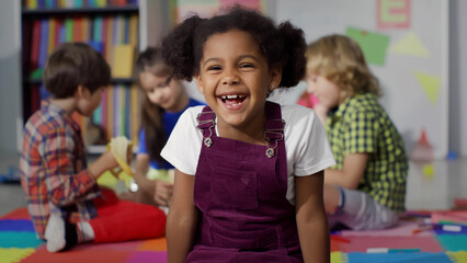 Close up portrait of smiling little African-American girl looking at camera at primary school