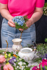Florist bei der Arbeit, Frau bindet frische Blumen zu einem kleinen Strauß mit Rosen,...