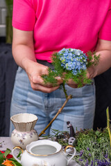 Florist bei der Arbeit, Frau bindet frische Blumen zu einem kleinen Strauß mit Rosen,...