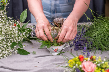 Florist arrangiert bunte Blumen in einem Gefäß aus Keramik, Blumengesteck mit frischen Blumen, 