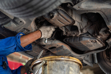 A mechanic works on the suspension of an elevated car in a repair facility.