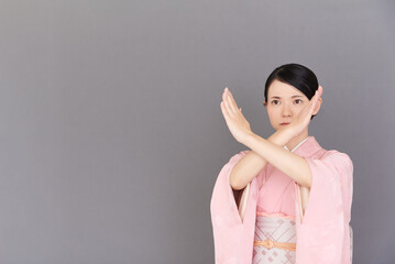 腕でバツ印を作る着物を着た女性