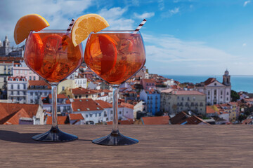 Two glasses of Spritz cocktail with view of Lisbon old town in Alfama district in Lisbon, Portugal