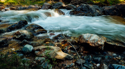 Close-up of mountain forest stream with clean icy water rapid flowing between rocky shores. Beautiful river background, long exposure.
