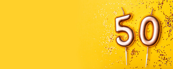 50 years celebration. Greeting banner. Gold candles in the form of number forty on yellow background with confetti.