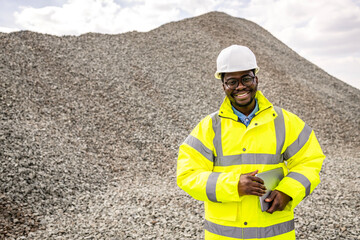 Portrait of road construction worker standing by large pile of rocks building material.