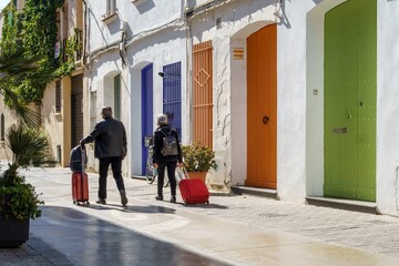 Couple of tourists with suitcases on the street of a Mediterranean village
