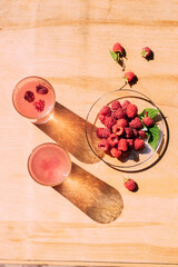 Ripe red raspberry drink in a transparent glass wooden background, summer seasonal food and refreshing drinks