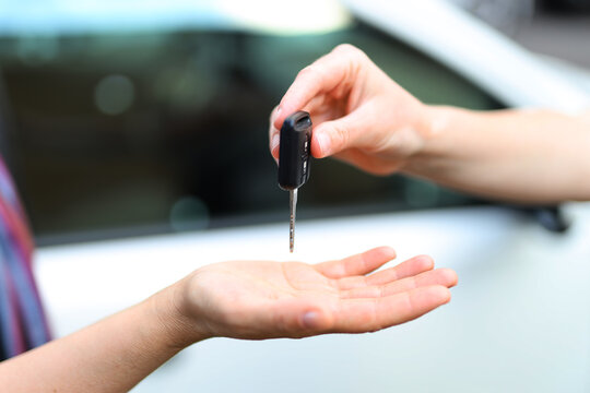 Pass the key from hand to hand, close-up on the background of the car, buying and selling rent.