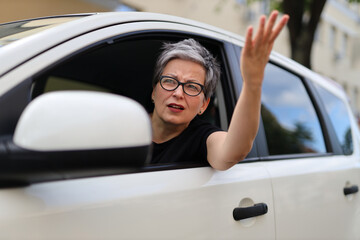 Angry and indignant female driver on the road in a car.