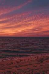 Fototapeta na wymiar Sonnenuntergang am Strand mit Blick auf das Meer und leuchtendem Himmel, Sardinien, Italien