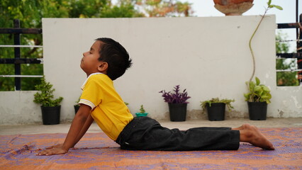 Little cute boy practicing yoga pose on a mat indoor. 