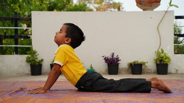 Little cute boy practicing yoga pose on a mat indoor. 