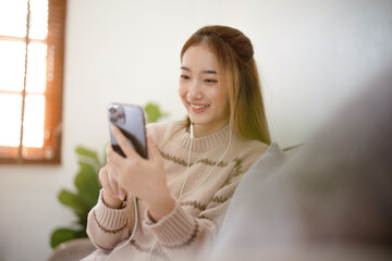 Happy asian woman using mobile phone and receiving good news.on sofa at living room. .