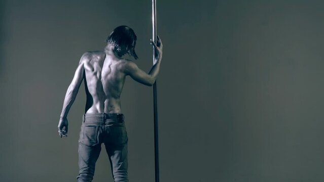 Flexible man exercises on pylon. Sexy flexible man demonstrates sexy flexible body. Flexibility stretching. Flexible female body. Pole dance. Male stripper. Strip dance, man pole dancing.