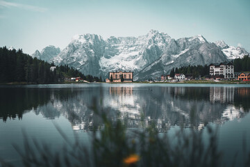 Lake misurina with a hotel and a snowy mountain in the background in the dolomites, italian alps. Hotel in the mountains that reflects in a lake