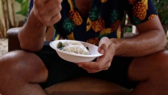 Candid moment of a tourist eating noam ango&rsquo;t Skor or khmer sticky rice dumpling with palm sugar, authentic traditional cambodian dessert